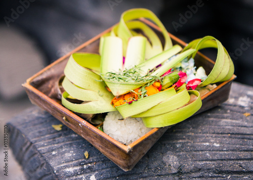 Fotografija Balinese Roadside Offerings
A basket made from coconut leafs and filled with flowers, rice and other offerings is placed on fences, roads or shrines to appease the Gods