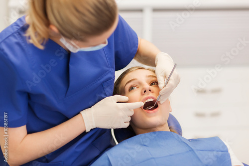 female dentist checking patient girl teeth