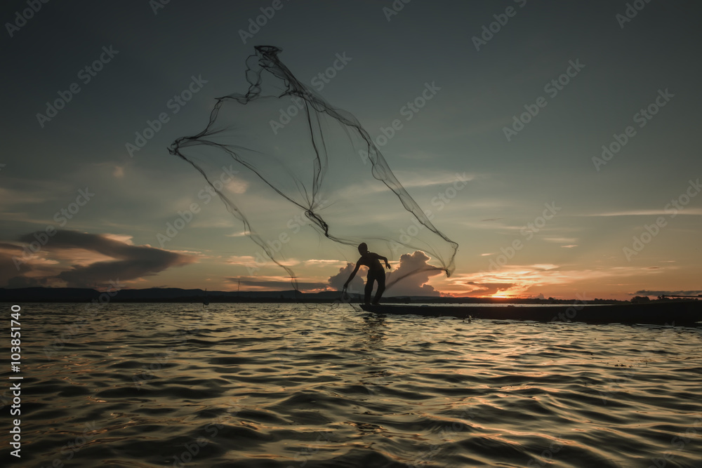 Fisherman throwing net at sunset