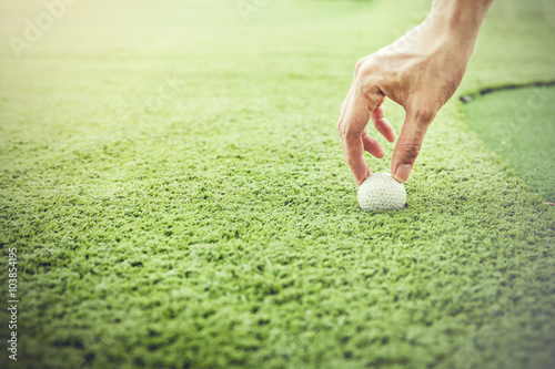 Golfer putting a golf ball onto green grass field - vintage aesthetics color tone