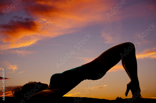 silhouette of woman in the sunset laying back with butt and knee
