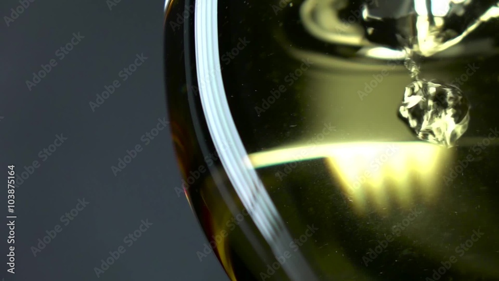 White wine being poured into a wineglass, grey, closeup, slowmotion White wine being poured into a wineglass, grey, closeup, slowmotion
