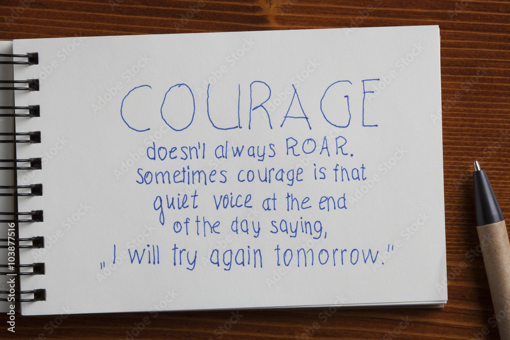 Courage handwritten text on a notebook with pen Courage handwritten text on a notebook with pen