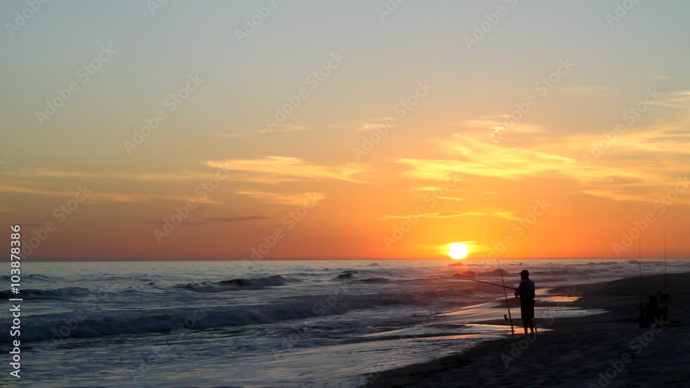 Beach fisherman stands by the seashore fishing with rods and reels at sunset on the Gulf of Mexico. Beach fisherman stands by the seashore fishing with rods and reels at sunset on the Gulf of Mexico.