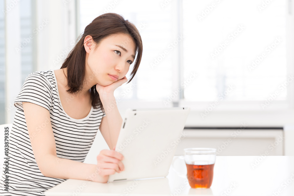 部屋でタブレットを見る女性 考える 部屋でタブレットを見る女性 考える