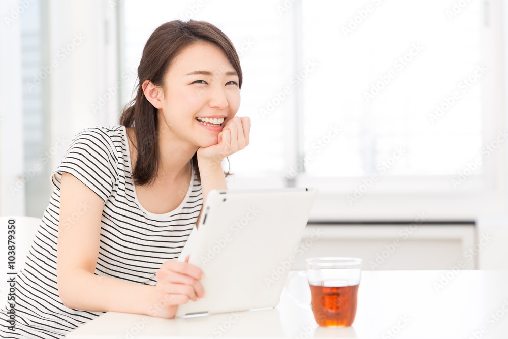 部屋でタブレットを見る女性 部屋でタブレットを見る女性