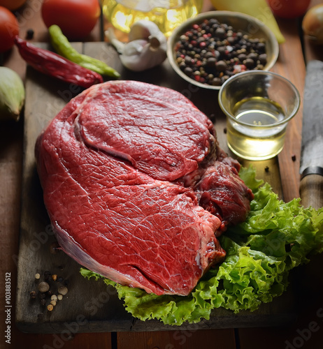 raw steak on the wooden background with spices and herbs