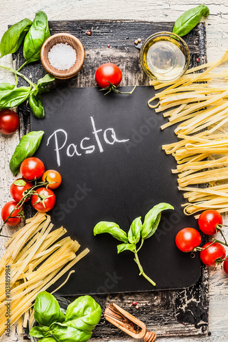 Pasta cooking background with chalkboard, tomatoes, basil and olive oil, top view. Italian food concept