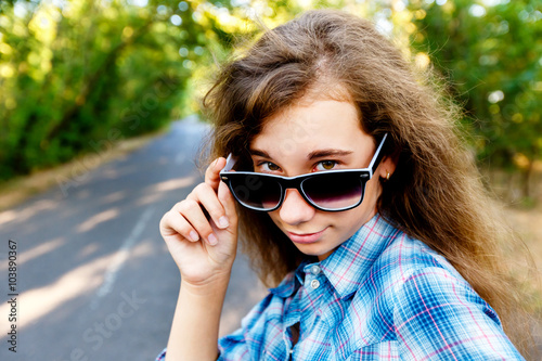 beautiful girl in black sunglasses on the road between the green © angor75