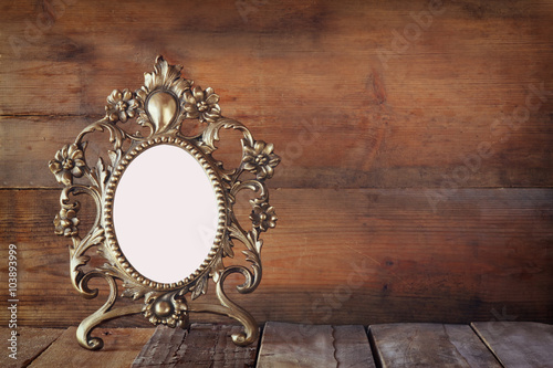 Antique blank victorian style frame on wooden table. vintage filtered image. template, ready to put photography 
