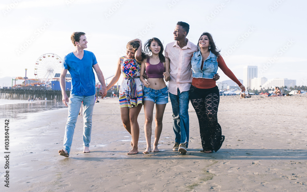 Fototapeta premium Mixed race group of friends walking in Santa monica beach