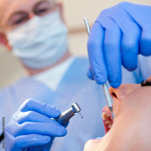 Dentist using dental drill. Focus on hands