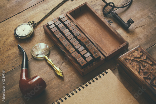 detective concept. Private Detective tools: magnifier glass, old keys, smoking pipe, notebook. top view. vintage filtered image

