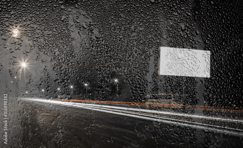 night view of the road through glass with raindrops