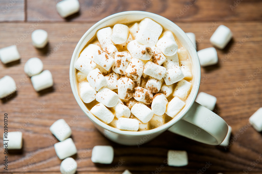 White cup of hot chocolate with marshmallows and cinnamon on dark wooden background. Flat lay. Top view White cup of hot chocolate with marshmallows and cinnamon on dark wooden background. Flat lay. Top view