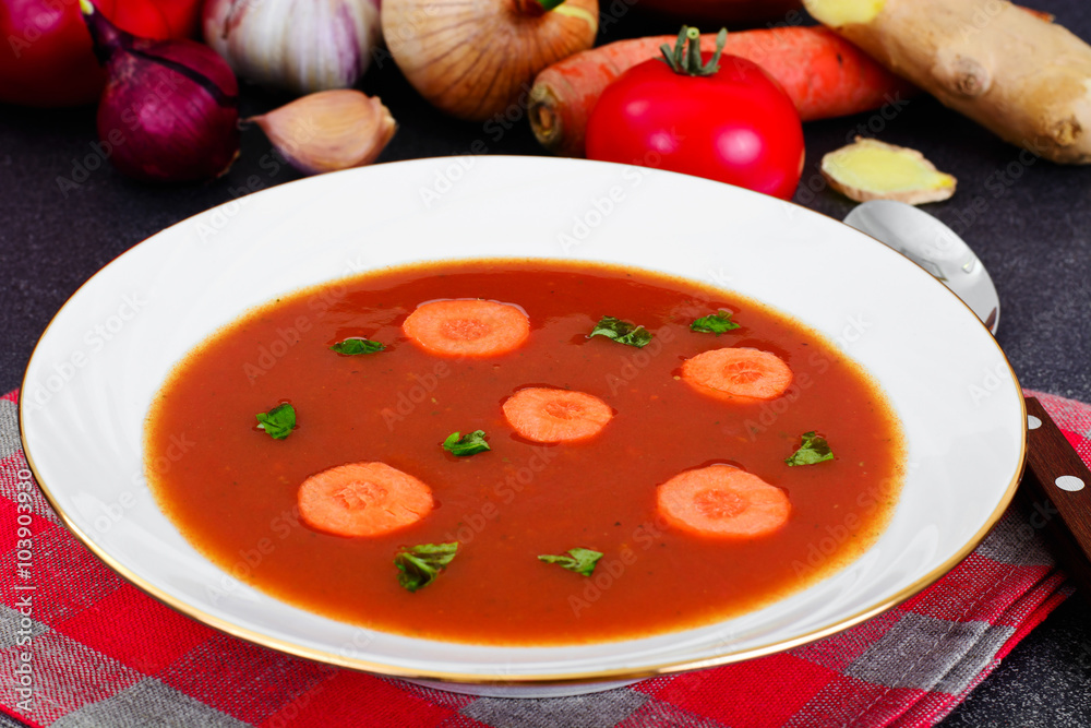 Carrot Tomato Soup in Plate. Behind lie on the soup ingredients,