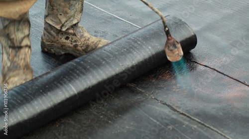 Installation of roll roofing waterproofing propane blowtorch during construction