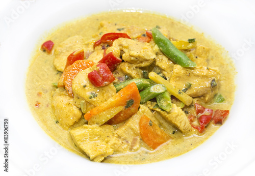 chicken curry with vegetables on a white plate in a restaurant