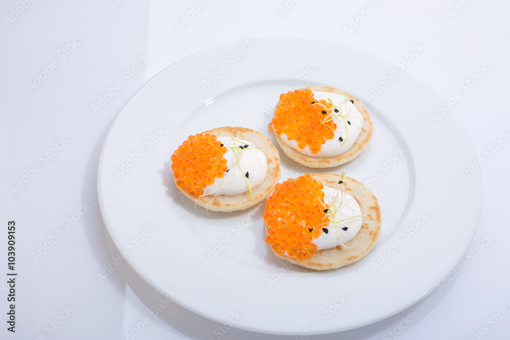 appetizer of caviar red in small pancakes with cream. homemade gourmet food. European cuisine