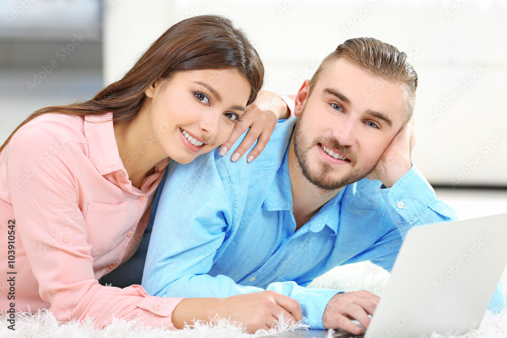 Happy couple lying on the floor and working on laptop