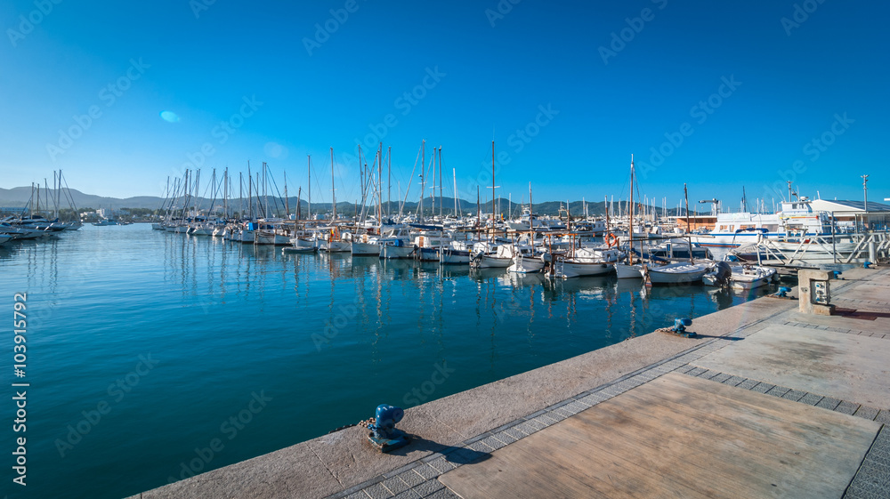 Sail boats idle in Ibiza marina harbor in the morning of a warm sunny day in St Antoni de Portmany Balearic Islands, Spain.  