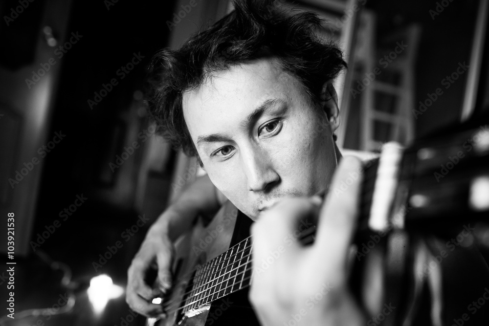 Crazy passionate guitarist playing guitar, black and white close-up portrait. Musician with disheveled hair.