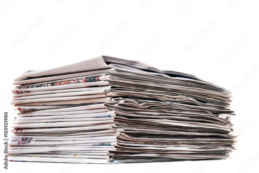 View of a pile of newspapers stacked isolated on a white background. View of a pile of newspapers stacked isolated on a white background.