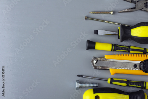 various forms of screws and screwdrivers and many other tools on grey wooden table
