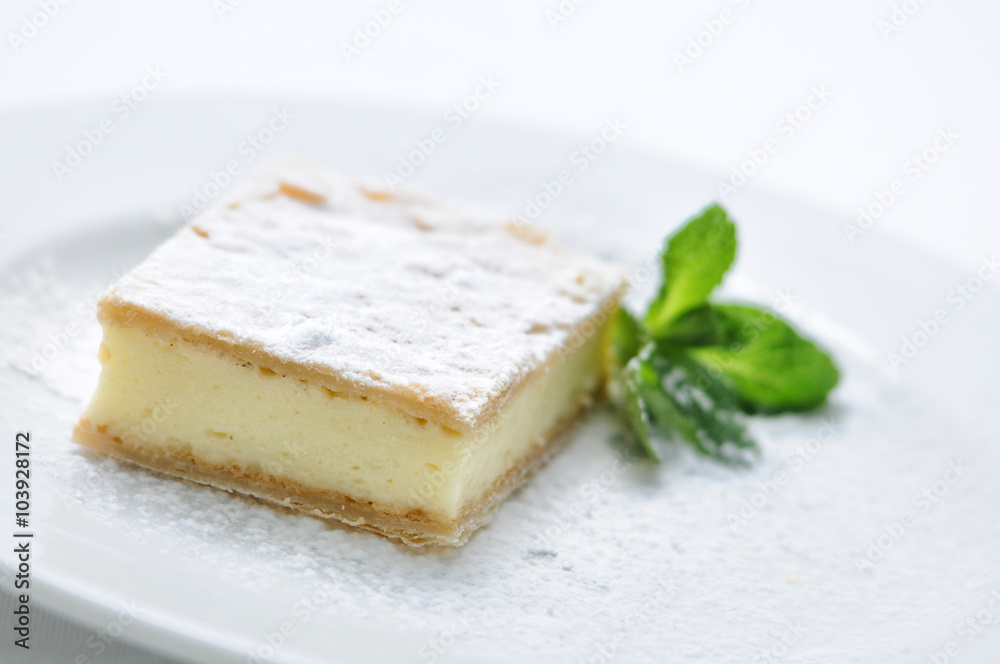 vanilla cream cake with sugar powder and mint leaf on white plate, sweet dessert or breakfast, patisserie, photography for shop