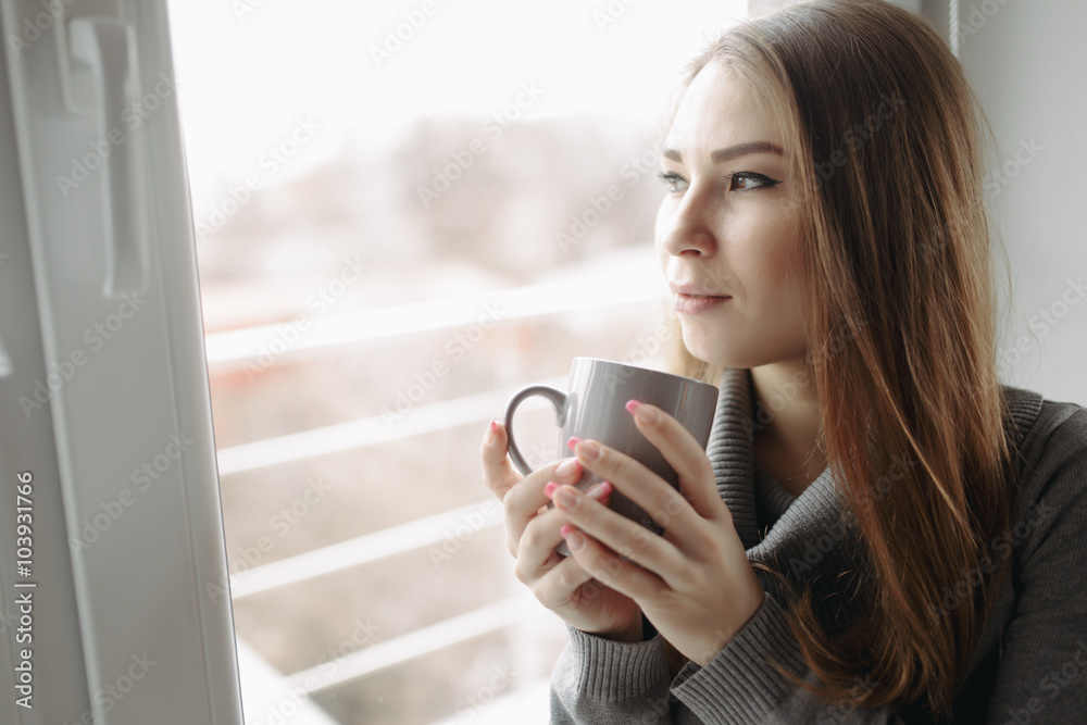 Attractive young woman sitting in a coffee shop at window