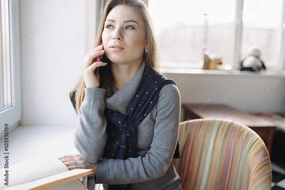 Beautiful young woman using her smartphone at window Beautiful young woman using her smartphone at window