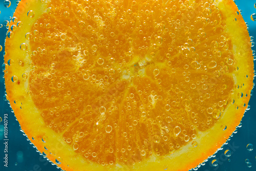 Soczysty plaster pomarańczy zanurzony w wodzie.
