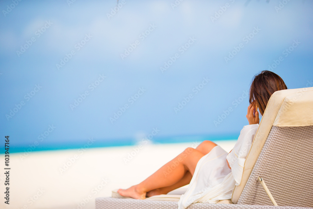 Young woman on lounger with mobile phone at the beach