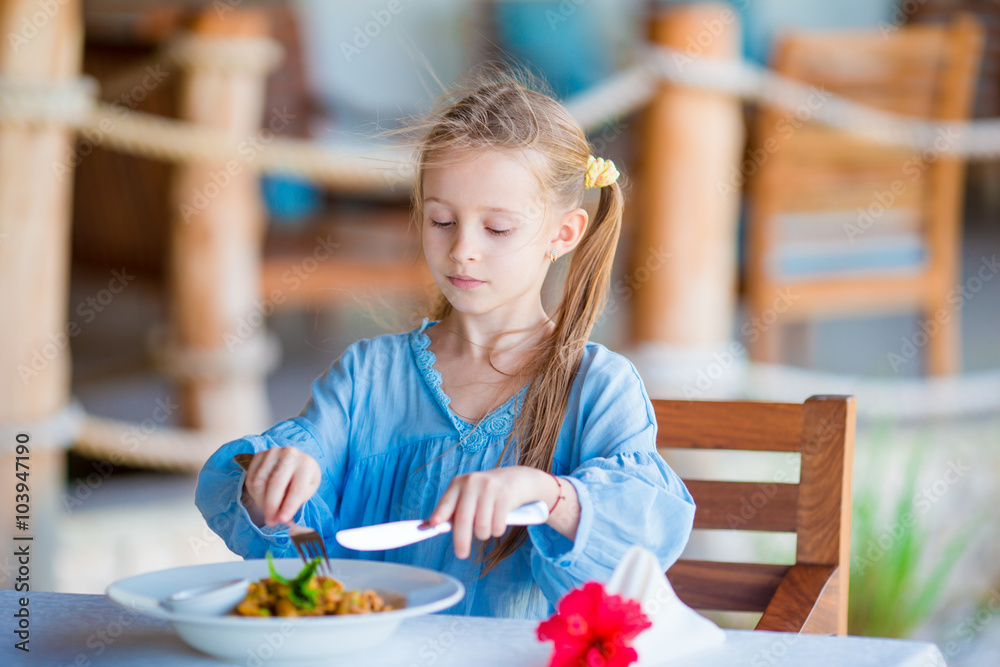 Adorable little girl having dinner at outdoor cafe