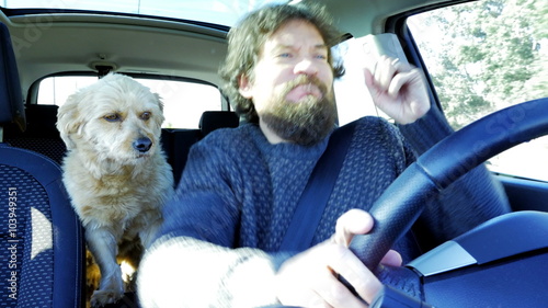 Happy man with beard dancing with dog in car having fun