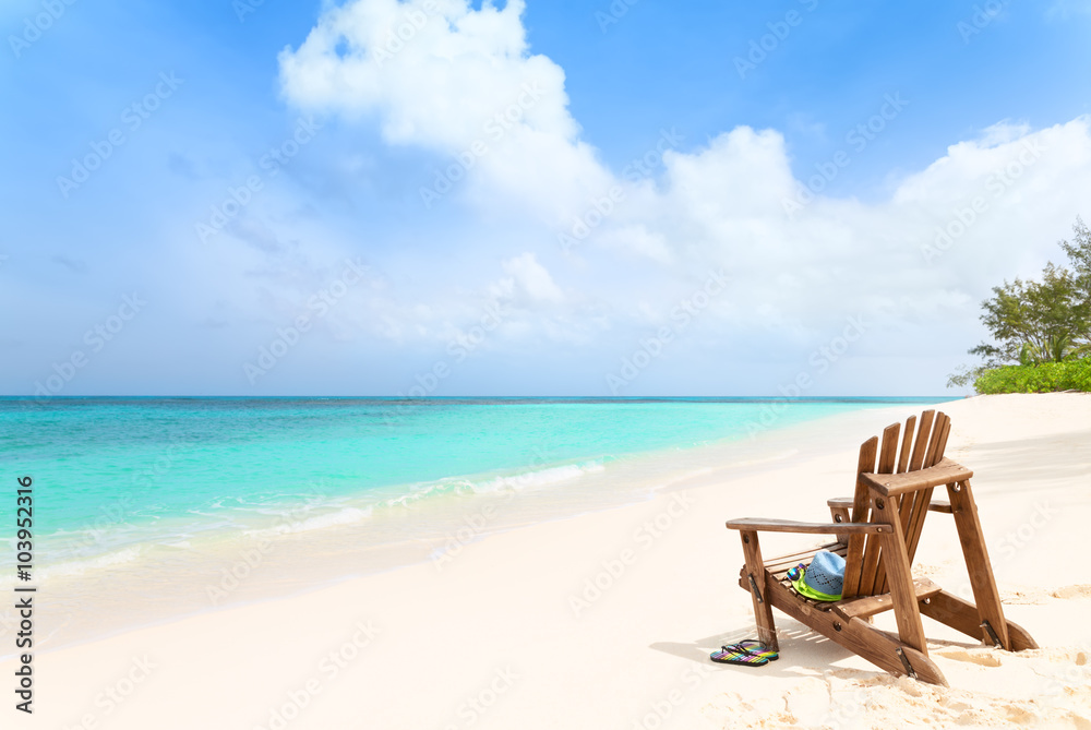 Wooden beach chair with hat and slippers at tropical beach, summ