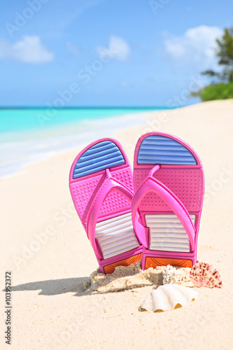 Pinks flip-flops on a sunny sandy beach..Tropical beach vacation