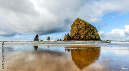 Oregon coast Haystack Rock on a dramatic cloudy day with reflections