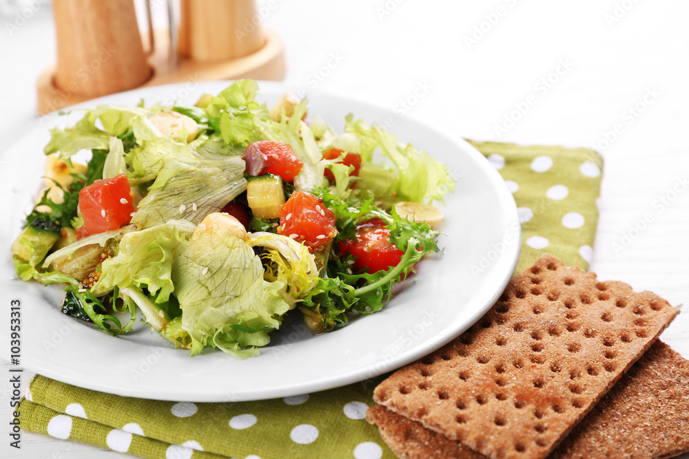 Tasty salmon salad on light wooden background