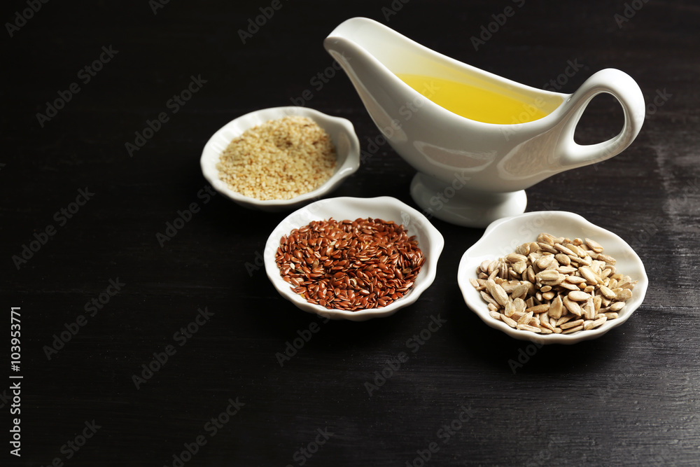Different kinds of seeds and oil on wooden table Different kinds of seeds and oil on wooden table