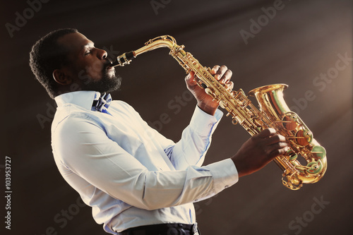 Photography African American jazz musician playing the saxophone on grey background