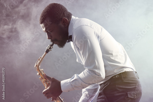 Canvas Print African American jazz musician playing the saxophone against colorful smoky back