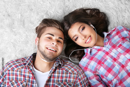 Teenager couple listening to music with earphones on a carpet