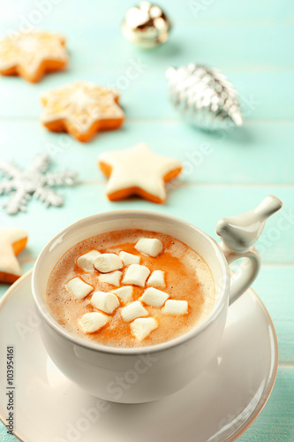 Cup of hot cacao with marshmallow and cookies on blue table