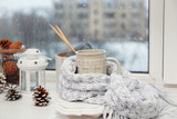 Cup of hot drink in on the windowsill in living room. Comfortable winter weekend or holidays at home