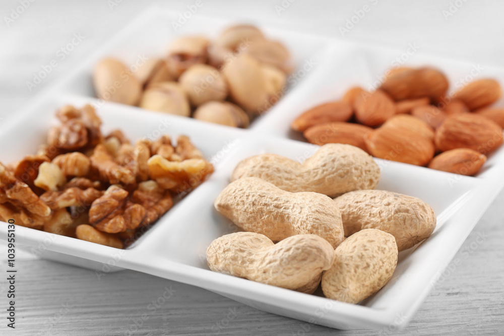 Walnut kernels, almonds, pistachios, peanuts in the ceramic rectangle plate, close-up Walnut kernels, almonds, pistachios, peanuts in the ceramic rectangle plate, close-up