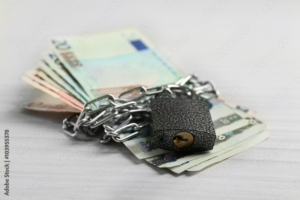 Euro banknotes with lock and chain on wooden table background Euro banknotes with lock and chain on wooden table background