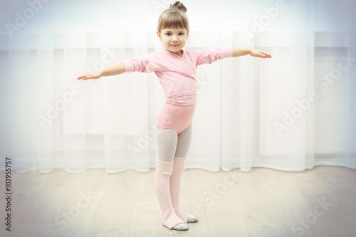 Fototapeta Naklejka Na Ścianę i Meble -  Little cute girl in pink leotard making new ballet movement at dance studio