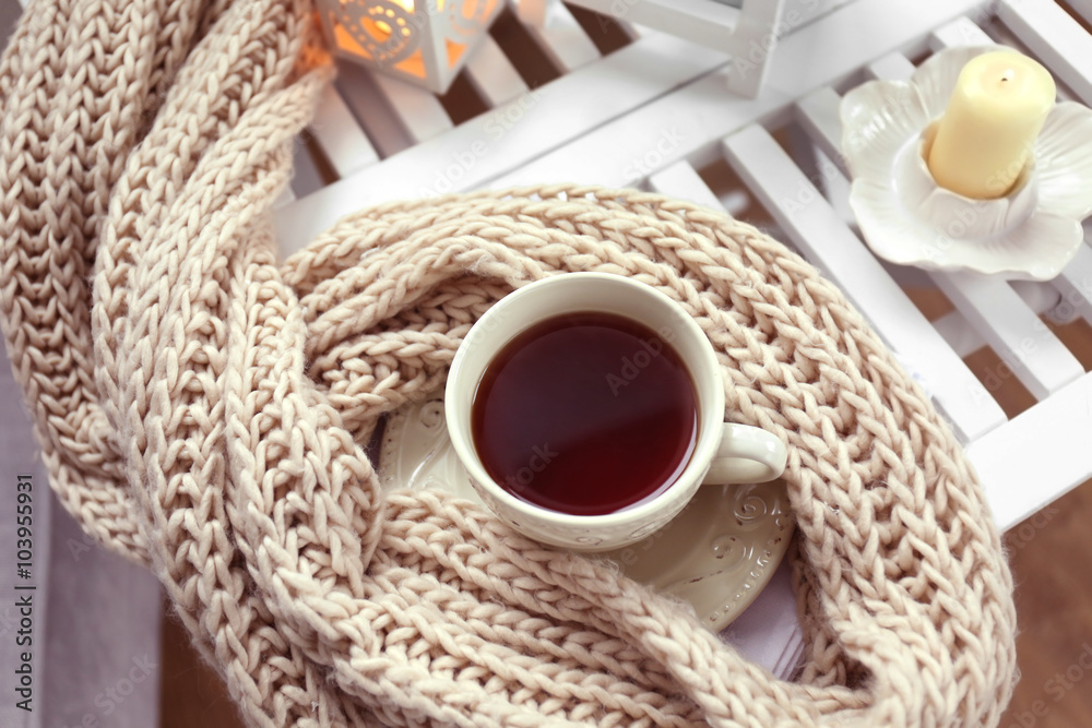Cup of tea and knitted scarf on coffee table in the room, close up Cup of tea and knitted scarf on coffee table in the room, close up