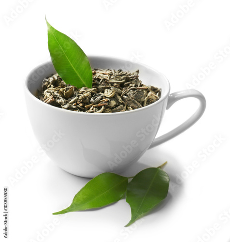 Cup with dry tea and green leaves, isolated on white